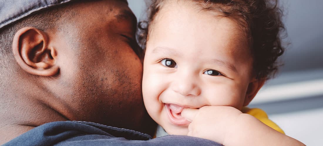 African American child smiling over dad's shoulder