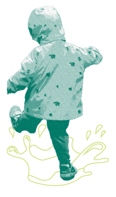 A young child wears a jacket and splashes in a puddle.