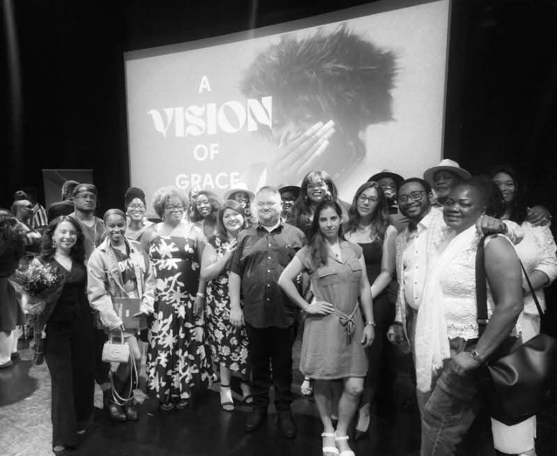 A group of people stand in front of a screen at the A Vision of Grace premiere in Houston.